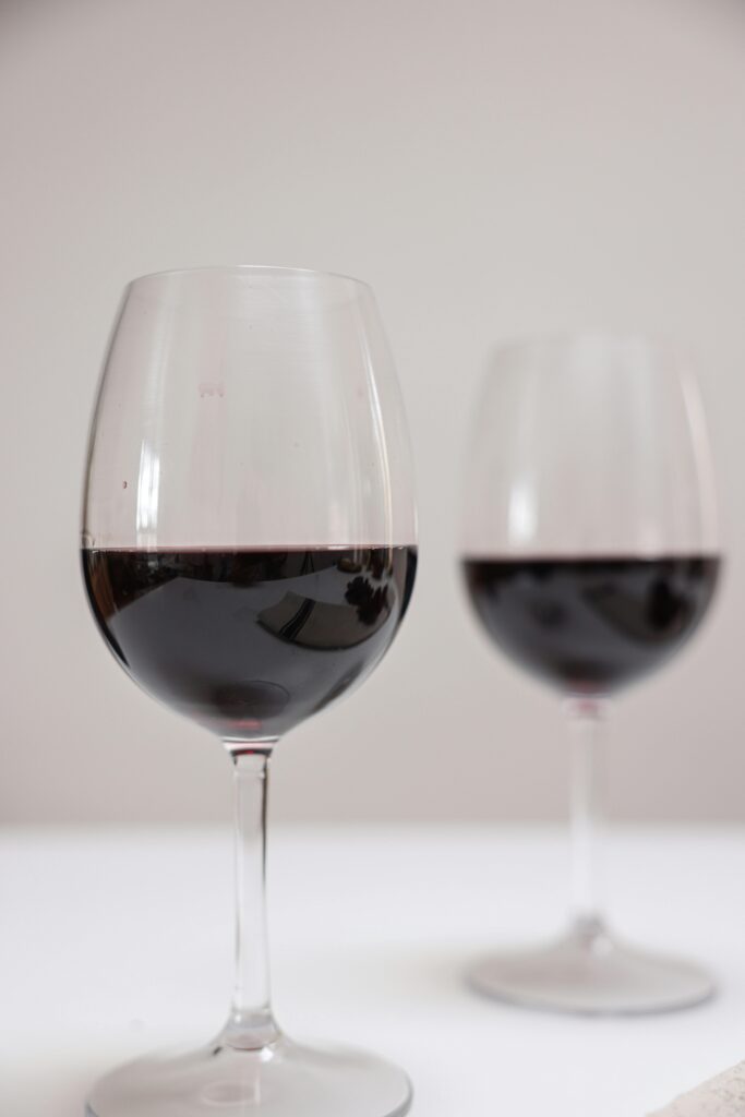 Two elegant red wine glasses placed on a white table, showcasing a minimalist style.